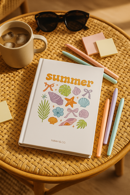 Hardcover white notebook with colorful summer-themed illustrations, including seashells, palm leaves, and bows, labeled “Summer Vibes” on the front.