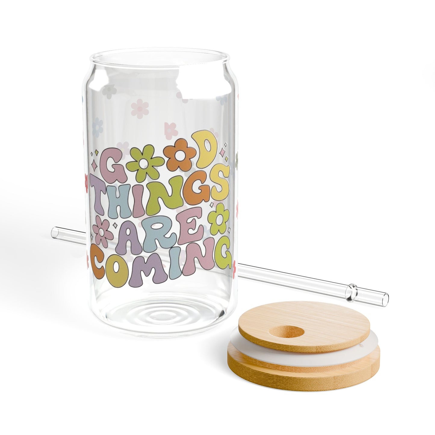 Clear glass tumbler with colorful text and floral designs, accompanied by a wooden lid and straw on a white background.