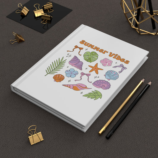 Notebook with 'Summer Vibes' design on a dark surface with stationery items.